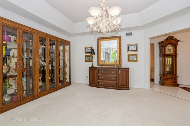 unfurnished room with light carpet, a notable chandelier, and a tray ceiling