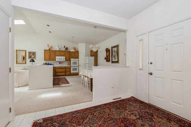 carpeted entryway featuring a notable chandelier and lofted ceiling