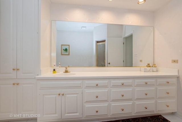 full bath with double vanity, a sink, a shower with shower door, and visible vents