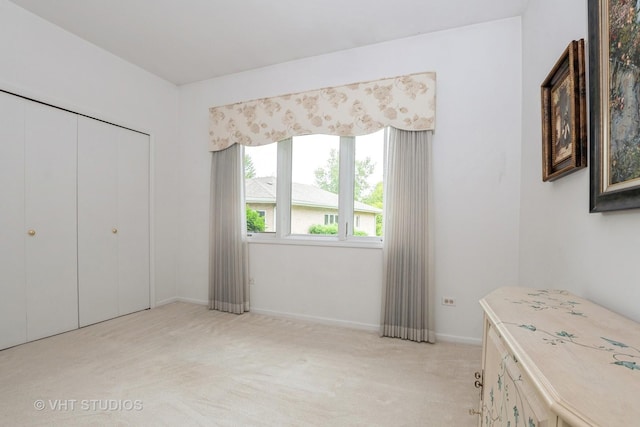 unfurnished bedroom featuring baseboards, a closet, and light colored carpet