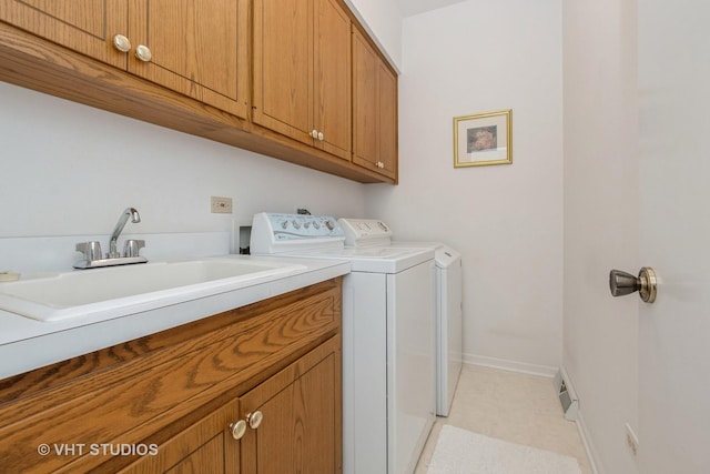 laundry room featuring baseboards, washing machine and dryer, cabinet space, and a sink