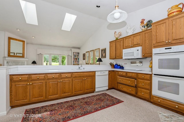kitchen featuring vaulted ceiling with skylight, light countertops, a sink, brown cabinets, and white appliances