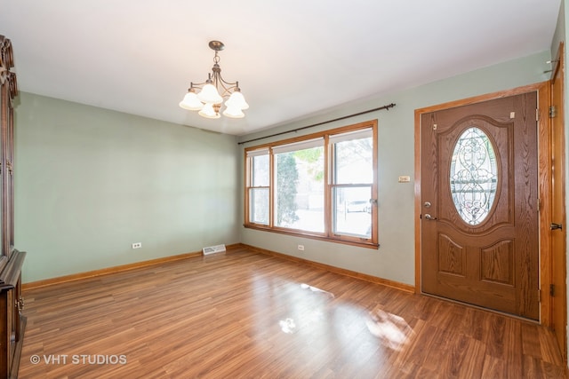 foyer entrance with a notable chandelier, hardwood / wood-style flooring, and a healthy amount of sunlight