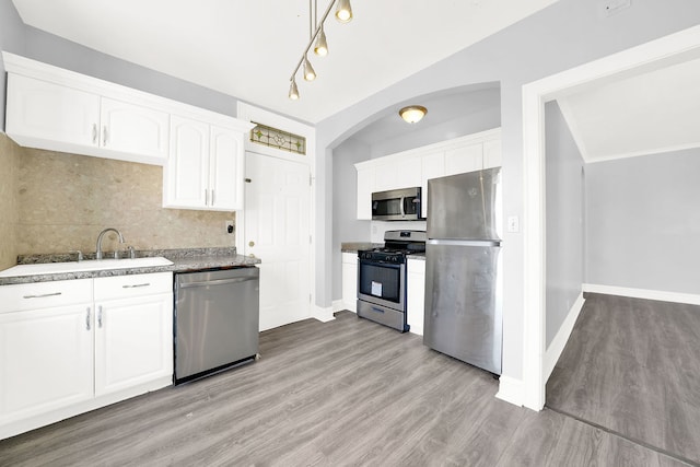 kitchen with sink, white cabinetry, light hardwood / wood-style flooring, decorative backsplash, and appliances with stainless steel finishes