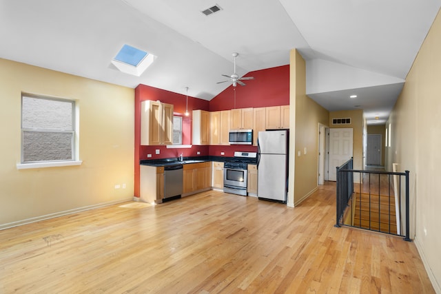 kitchen with ceiling fan, pendant lighting, a skylight, high vaulted ceiling, and stainless steel appliances