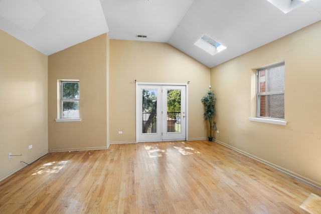 unfurnished room with lofted ceiling with skylight and light hardwood / wood-style floors