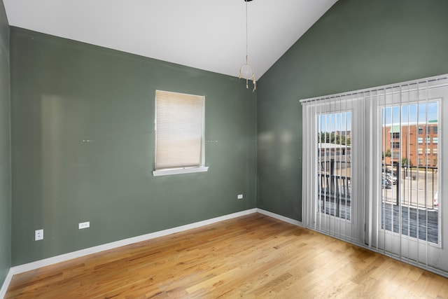 unfurnished room featuring wood-type flooring, plenty of natural light, and high vaulted ceiling