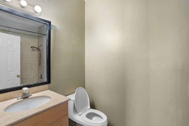 bathroom with tiled shower, vanity, and toilet