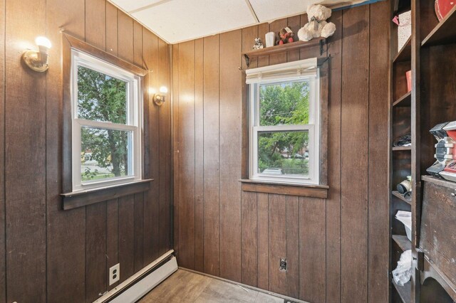 unfurnished room featuring wooden walls and baseboard heating