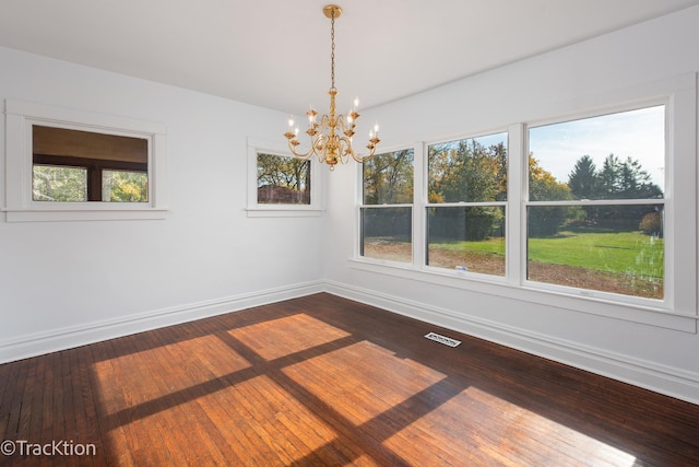 unfurnished dining area featuring a wealth of natural light, wood-type flooring, and a notable chandelier