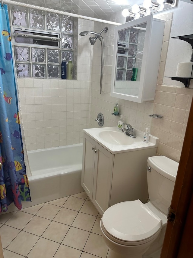 full bathroom featuring tile patterned floors, toilet, shower / bath combination with curtain, vanity, and tile walls