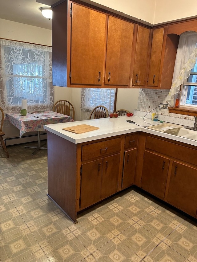 kitchen featuring kitchen peninsula, a baseboard heating unit, a healthy amount of sunlight, and sink