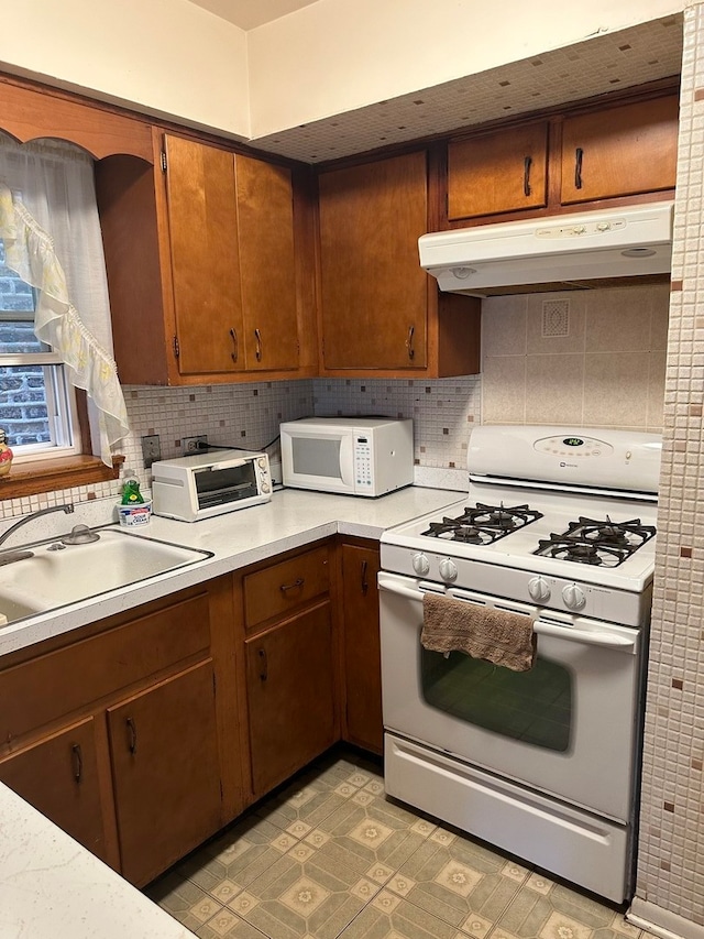 kitchen featuring decorative backsplash, sink, and white appliances