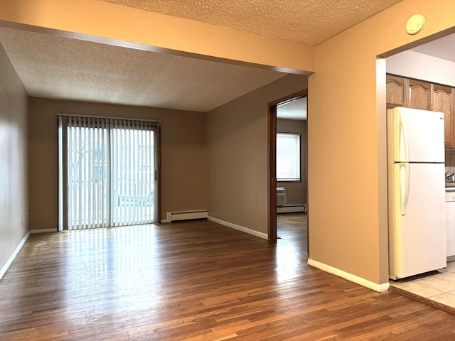 spare room with baseboard heating, a textured ceiling, and hardwood / wood-style flooring