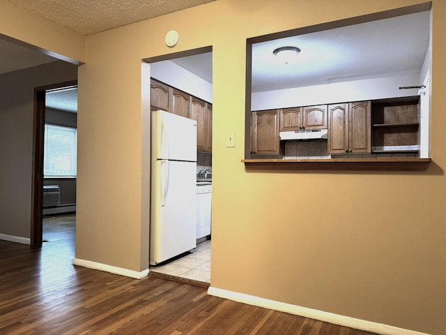 kitchen with hardwood / wood-style floors, white appliances, a textured ceiling, and dark brown cabinets