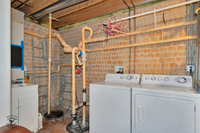 clothes washing area featuring brick wall and washing machine and dryer