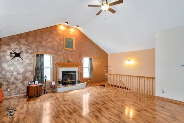 unfurnished living room featuring lofted ceiling, a tiled fireplace, ceiling fan, and hardwood / wood-style flooring