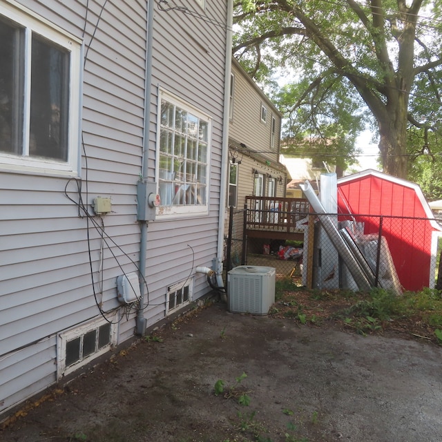 view of property exterior featuring a deck, a storage unit, and central air condition unit