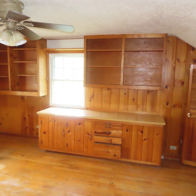 kitchen with wooden walls, light hardwood / wood-style floors, ceiling fan, and a textured ceiling