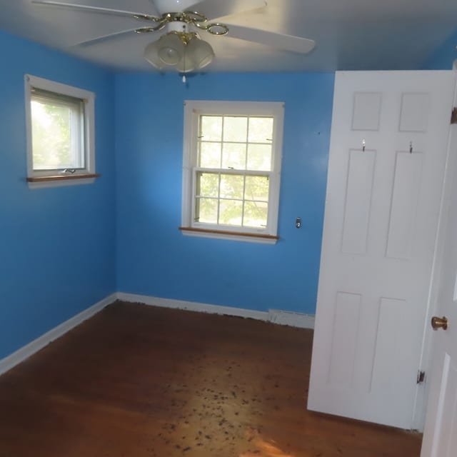 unfurnished room featuring ceiling fan, dark hardwood / wood-style flooring, and a wealth of natural light