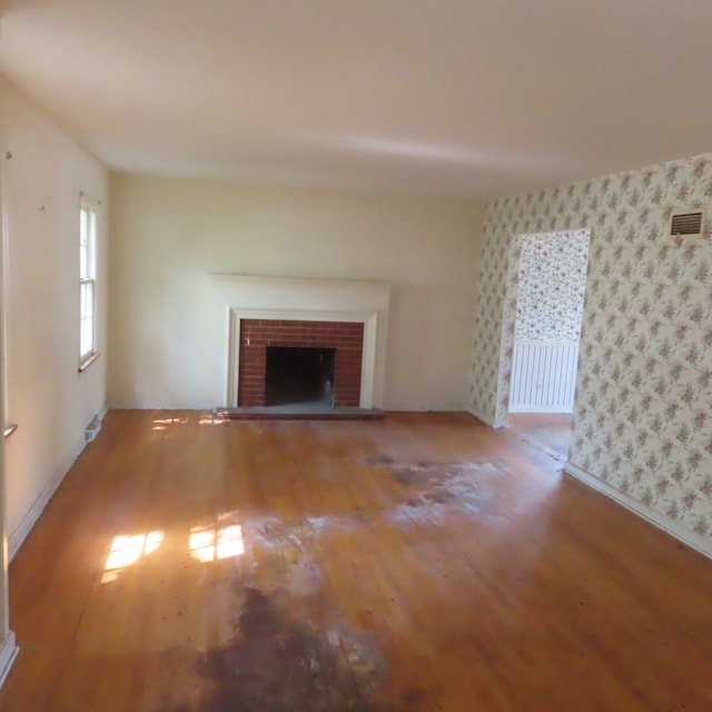 unfurnished living room with a brick fireplace and wood-type flooring