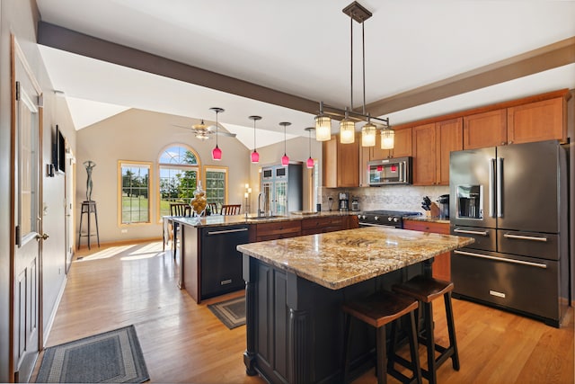 kitchen with pendant lighting, premium appliances, a kitchen island, a kitchen bar, and kitchen peninsula