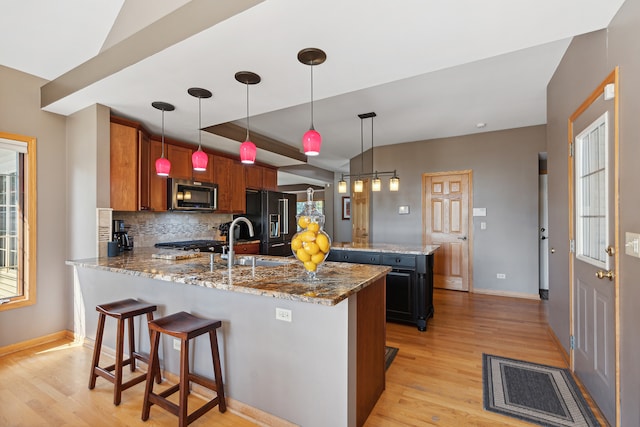 kitchen with decorative backsplash, sink, hanging light fixtures, and dark stone counters