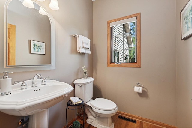 bathroom with toilet, wood-type flooring, and sink