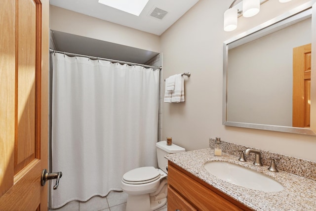 bathroom featuring tile patterned flooring, vanity, toilet, and a skylight