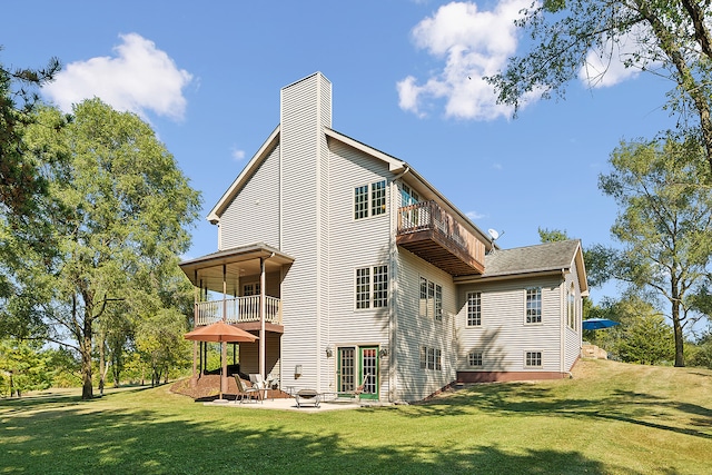 rear view of property featuring a yard, a patio, and a balcony