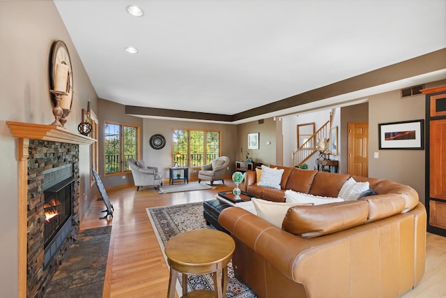 living room with a stone fireplace and light hardwood / wood-style flooring