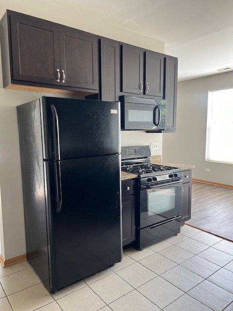 kitchen with light tile patterned floors, baseboards, black appliances, and visible vents