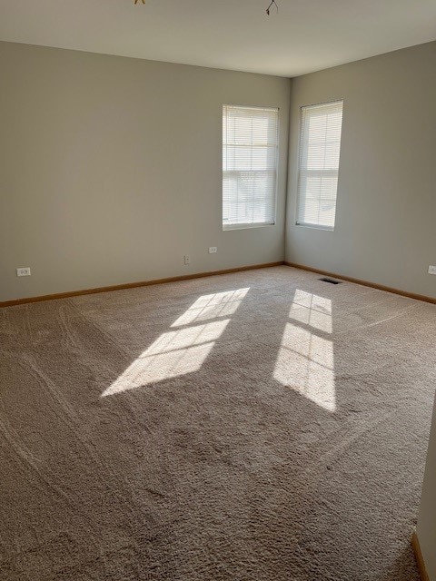 carpeted spare room featuring baseboards and visible vents