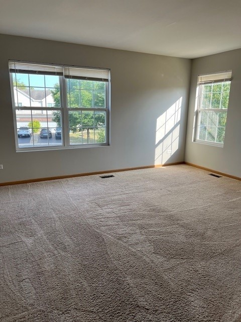 carpeted spare room with baseboards and visible vents