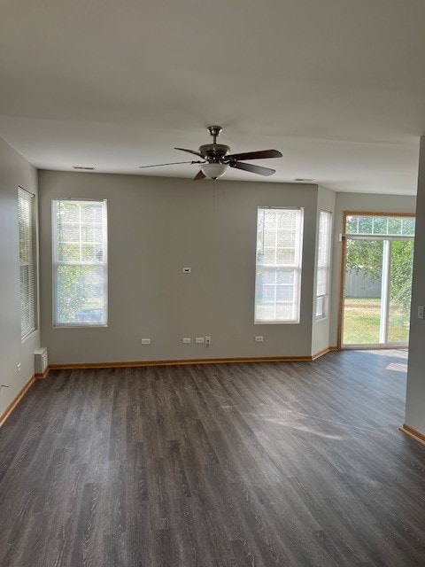 unfurnished room featuring ceiling fan, dark wood-type flooring, and a healthy amount of sunlight