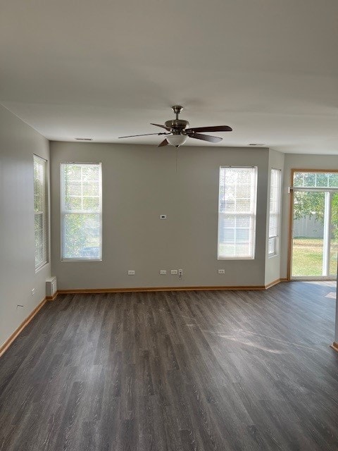 spare room featuring a wealth of natural light, ceiling fan, and dark wood-type flooring