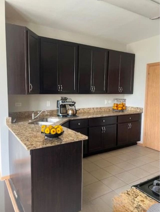 kitchen featuring a sink, light stone countertops, a peninsula, and light tile patterned flooring