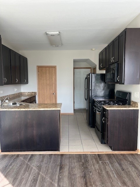 kitchen with a peninsula, light wood-style floors, baseboards, a sink, and black appliances