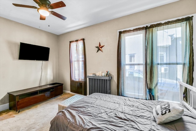 carpeted bedroom with ceiling fan, radiator, and multiple windows