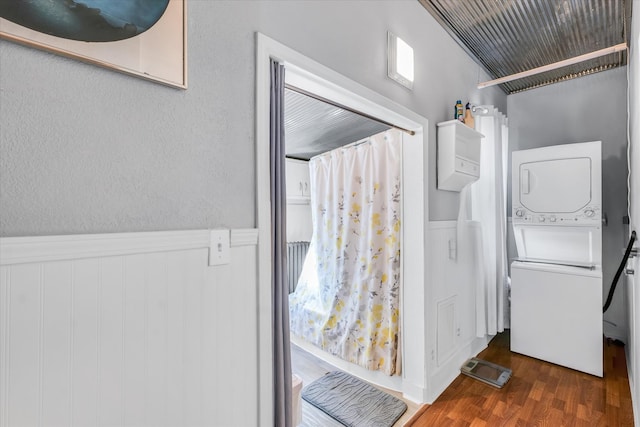 interior space featuring stacked washer / drying machine and dark wood-type flooring