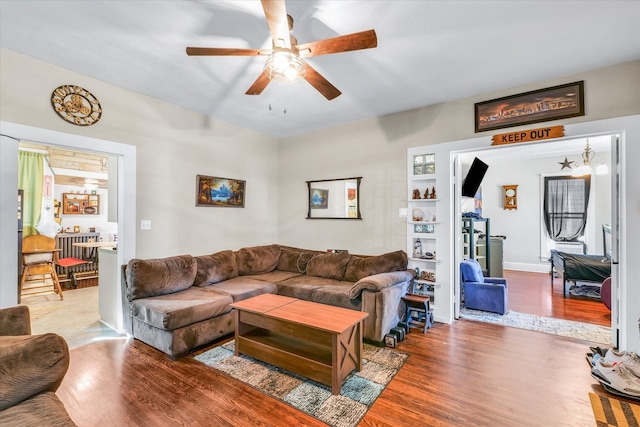 living room with hardwood / wood-style flooring and ceiling fan with notable chandelier