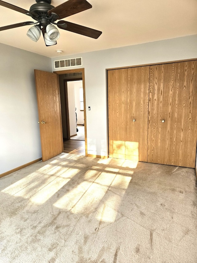 unfurnished bedroom with a closet, light colored carpet, and ceiling fan