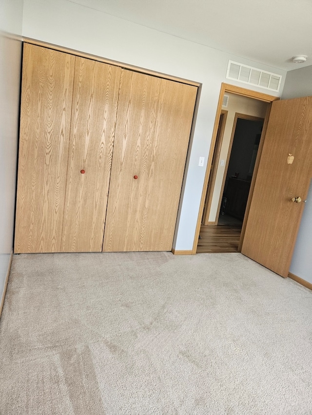 unfurnished bedroom with light colored carpet and a closet