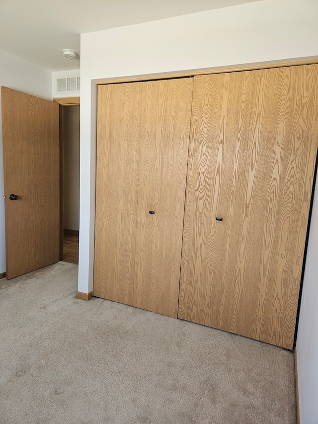 unfurnished bedroom with light colored carpet and a closet