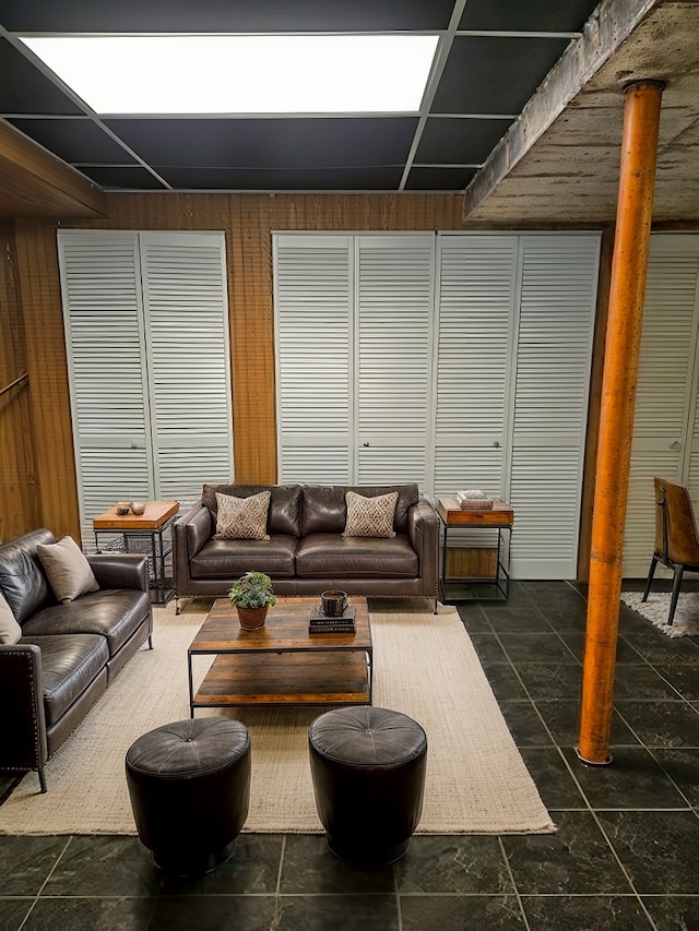 living room with dark tile patterned floors and wood walls