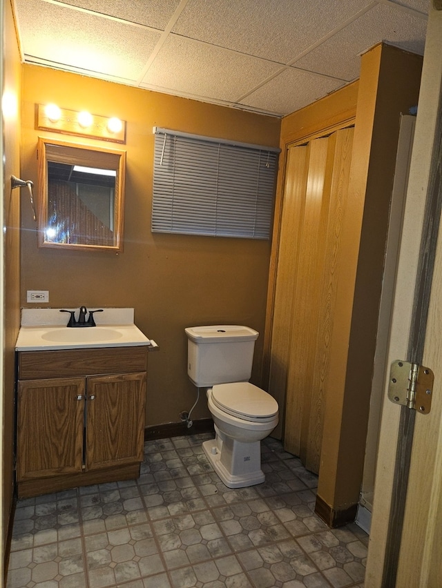 bathroom featuring vanity, a drop ceiling, toilet, and tile patterned floors