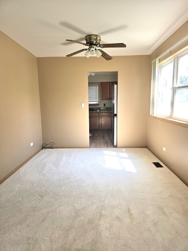 carpeted spare room featuring ceiling fan