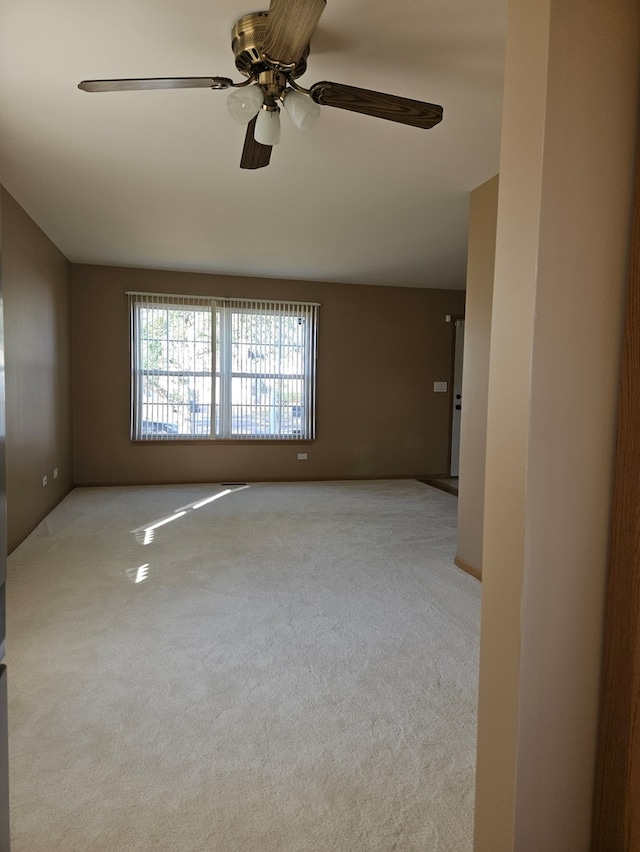 carpeted spare room featuring ceiling fan