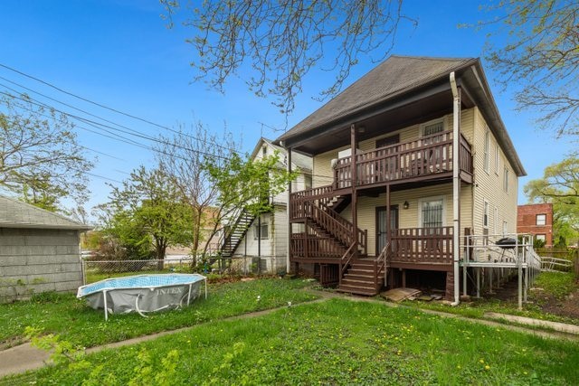 back of house featuring a lawn and a pool side deck