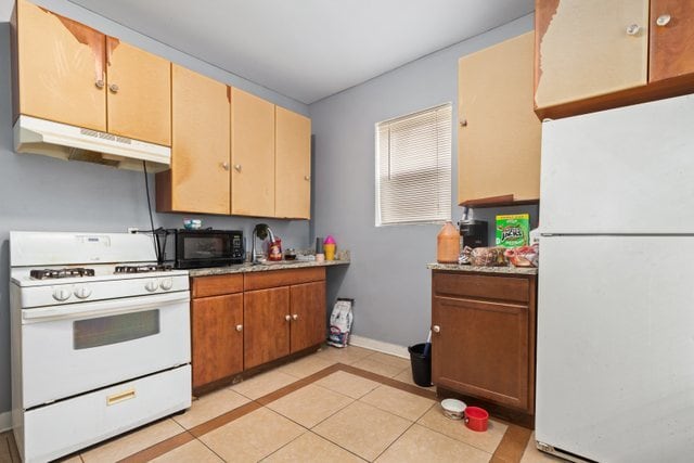 kitchen featuring light tile patterned flooring and white appliances